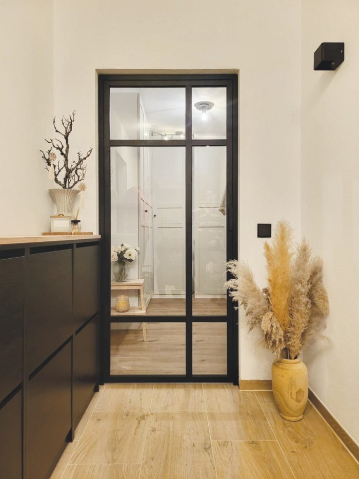 Schwarze Loft-Drehtür aus Aluminium und Glas als elegante Verbindung zwischen Flur und Wohnraum.