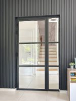 Moderne Loft-Drehtür aus Aluminium und Glas in schwarzem Rahmen als stilvoller Blickfang im Wohnbereich.
